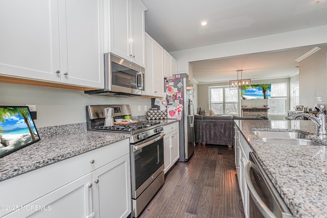 kitchen featuring crown molding, appliances with stainless steel finishes, dark wood-type flooring, white cabinets, and a sink