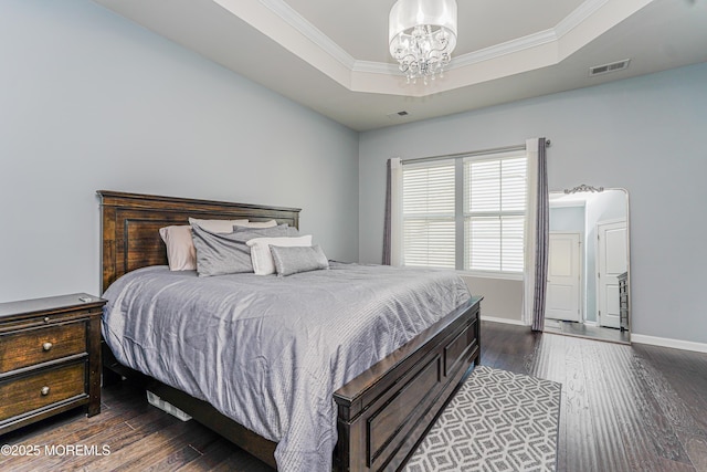 bedroom featuring ornamental molding, a tray ceiling, dark wood-style flooring, and visible vents