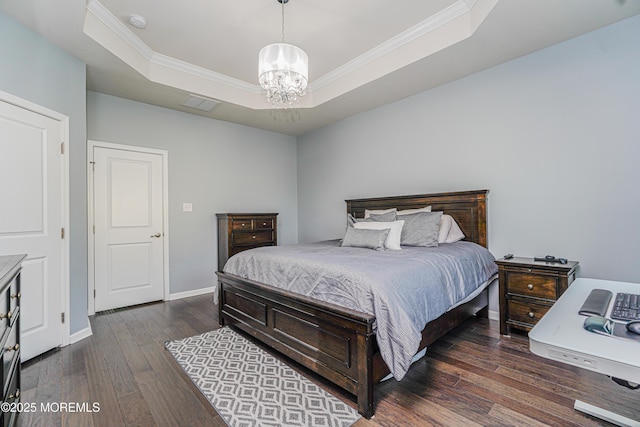 bedroom featuring baseboards, a raised ceiling, hardwood / wood-style flooring, ornamental molding, and an inviting chandelier