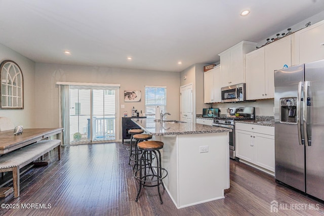 kitchen with a kitchen island with sink, appliances with stainless steel finishes, dark wood finished floors, and white cabinetry