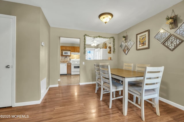 dining space with visible vents, light wood-style floors, and baseboards