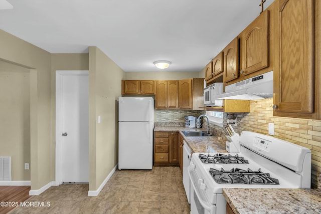 kitchen with white appliances, baseboards, a sink, under cabinet range hood, and backsplash