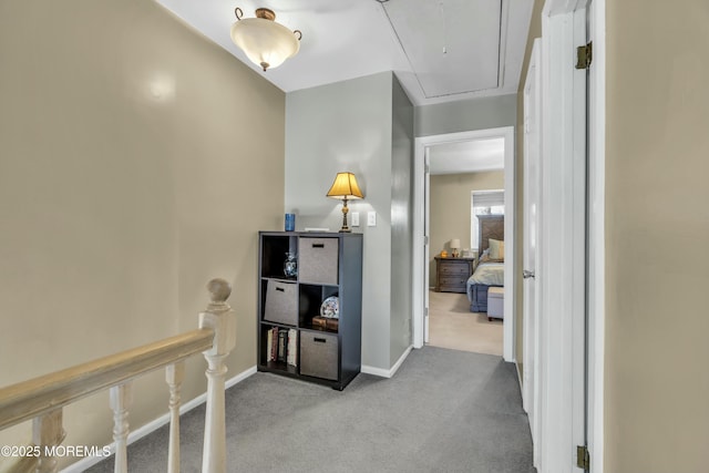 hallway with baseboards, carpet floors, attic access, and an upstairs landing