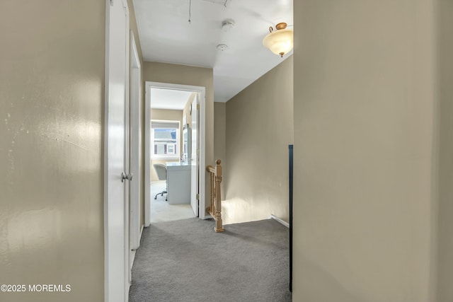 hallway with an upstairs landing, carpet flooring, and attic access