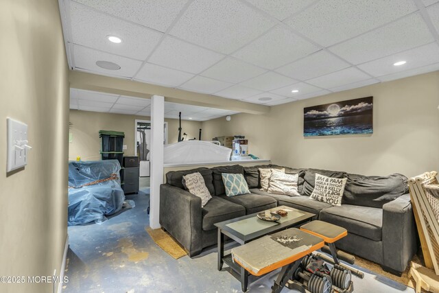 living room with unfinished concrete flooring, recessed lighting, and a paneled ceiling