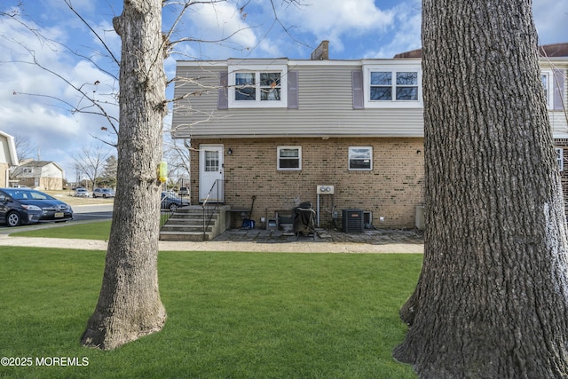 exterior space with brick siding, central AC, a chimney, and a yard