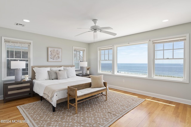 bedroom featuring light wood finished floors, visible vents, baseboards, a water view, and recessed lighting