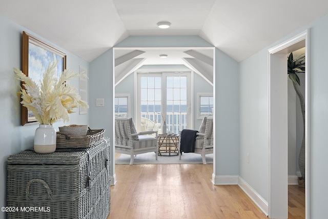 interior space featuring baseboards, vaulted ceiling, and light wood finished floors