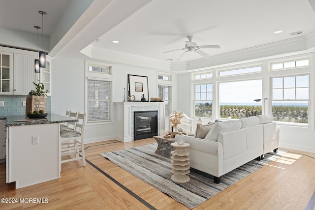 living area with light wood-style floors, a wealth of natural light, a glass covered fireplace, and baseboards