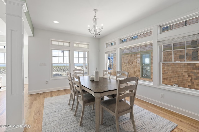 dining space featuring a chandelier, light wood-type flooring, decorative columns, and baseboards