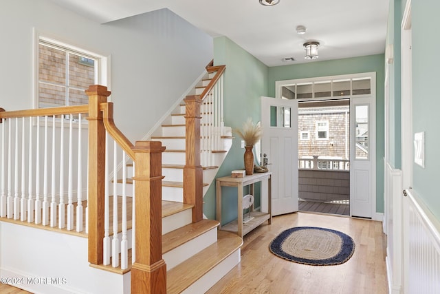 foyer entrance featuring visible vents, stairway, and wood finished floors