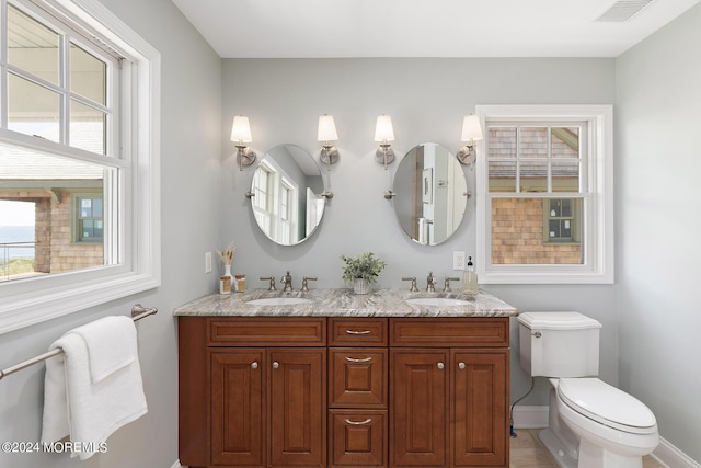 full bath featuring visible vents, double vanity, a sink, and toilet