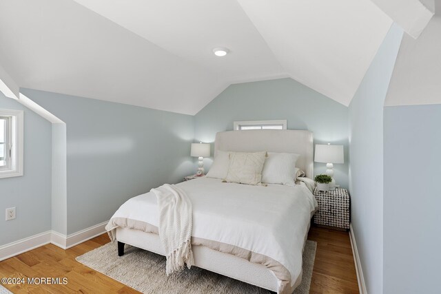 bedroom featuring vaulted ceiling, baseboards, and wood finished floors