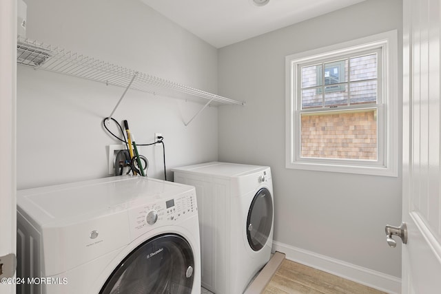 laundry room featuring baseboards, laundry area, light wood finished floors, and washer and dryer