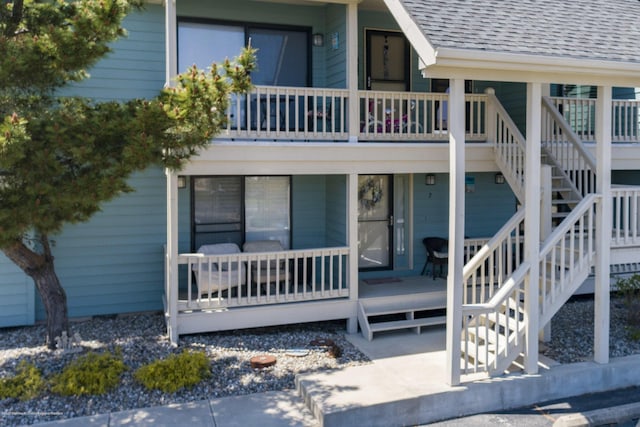 exterior space featuring stairway, a porch, and roof with shingles