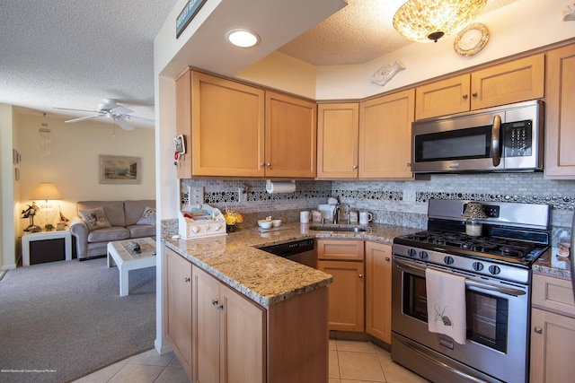 kitchen featuring light tile patterned flooring, a peninsula, stainless steel appliances, and a sink