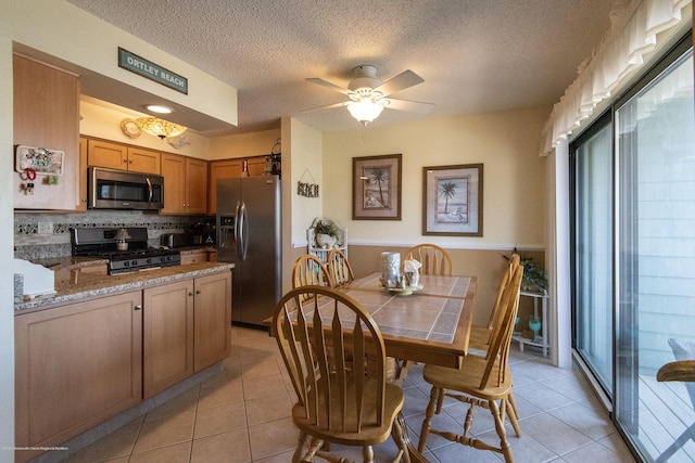 dining space featuring ceiling fan, light tile patterned floors, and a textured ceiling