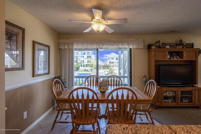 dining area with a textured ceiling, tile patterned floors, baseboards, and ceiling fan