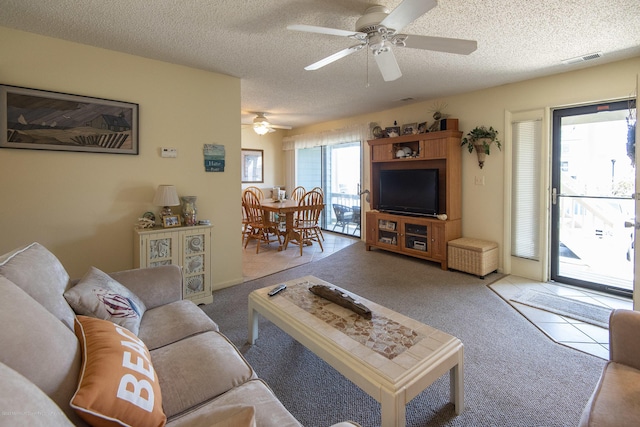 living room featuring visible vents, carpet floors, tile patterned floors, a textured ceiling, and a ceiling fan