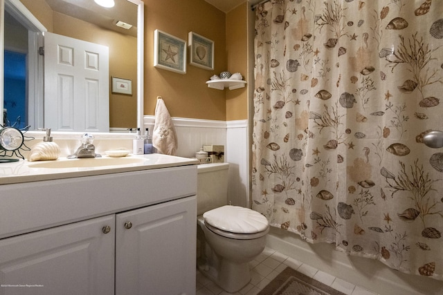 full bathroom featuring vanity, a wainscoted wall, shower / bath combo, tile patterned flooring, and toilet