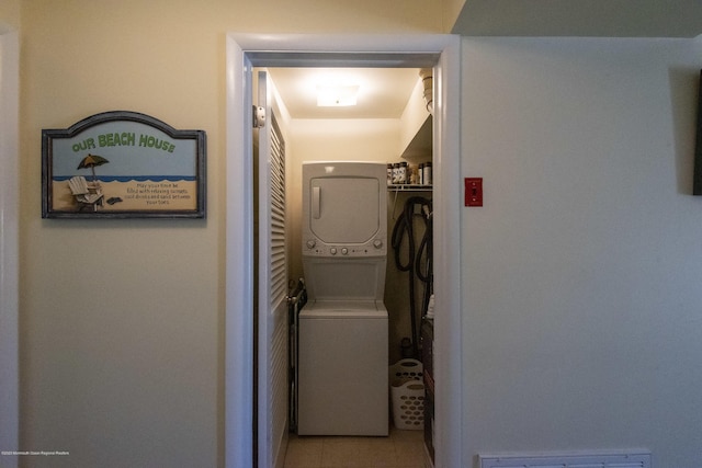 laundry area with light tile patterned floors, visible vents, and stacked washer / dryer