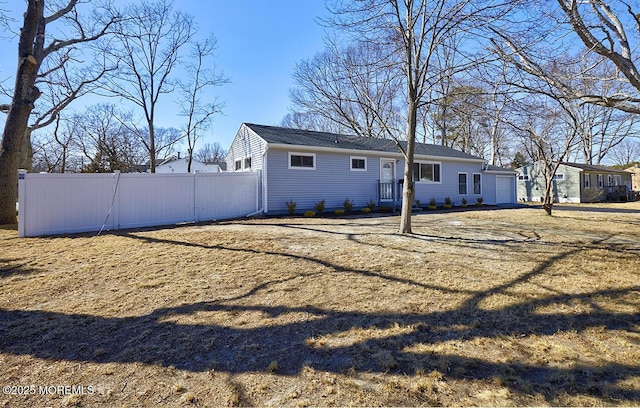 rear view of property with a garage and fence