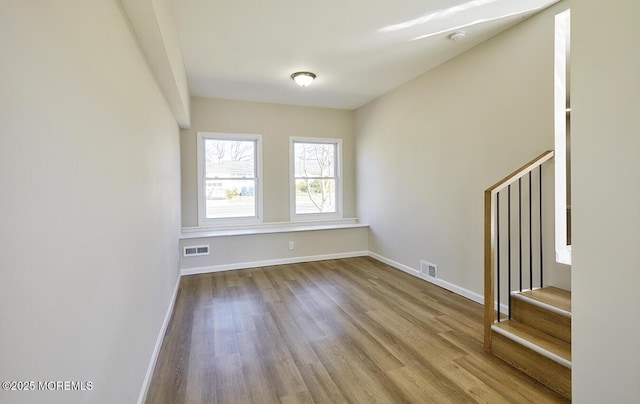 spare room featuring stairs, wood finished floors, and visible vents