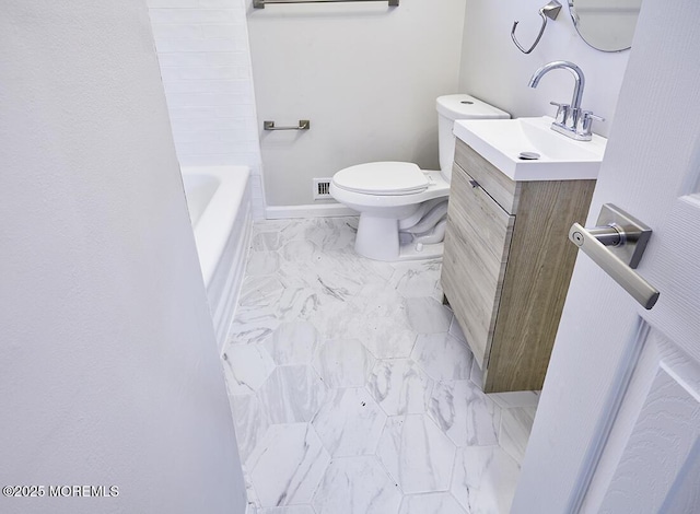 bathroom with a washtub, toilet, vanity, baseboards, and marble finish floor