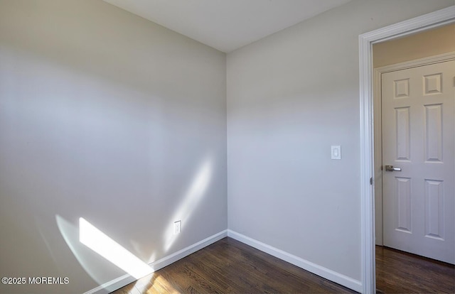 spare room with dark wood-style flooring and baseboards