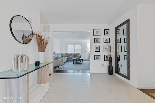 hallway featuring light tile patterned floors and visible vents