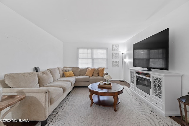 living room featuring baseboards, wood finished floors, and a glass covered fireplace