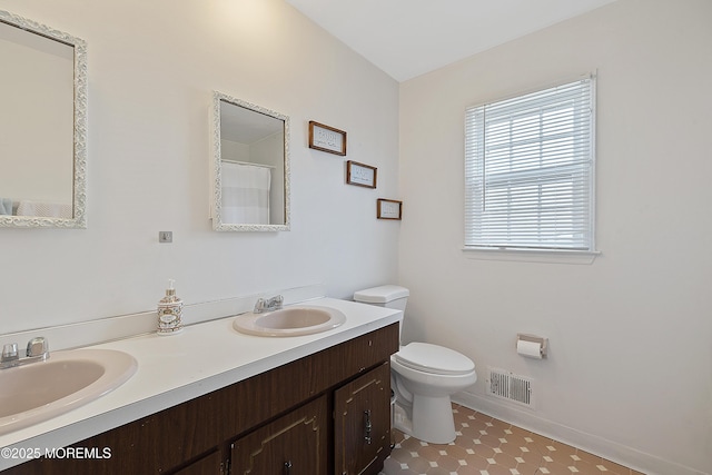 bathroom with toilet, double vanity, a sink, and visible vents