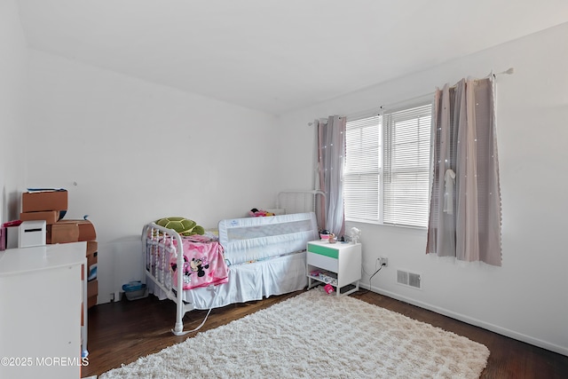 bedroom featuring baseboards, visible vents, and wood finished floors