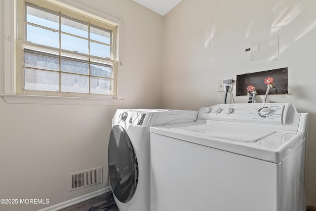 clothes washing area with washing machine and dryer, laundry area, visible vents, and baseboards