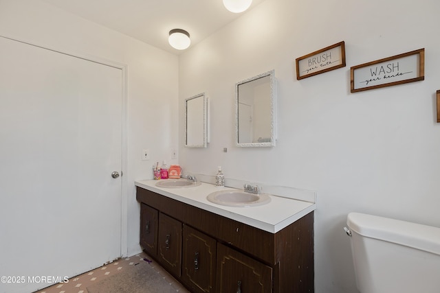 bathroom with a sink, toilet, and double vanity