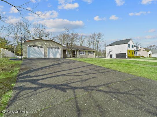 view of front of home with a garage, aphalt driveway, and a front yard