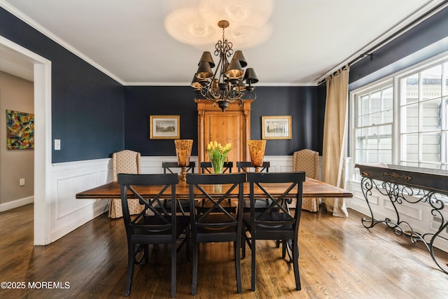 dining area featuring an inviting chandelier, wood finished floors, a wainscoted wall, and ornamental molding