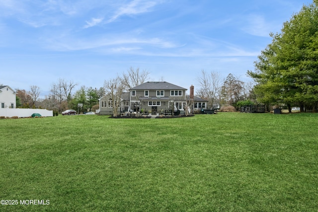 rear view of property featuring a patio, a yard, fence, and a chimney