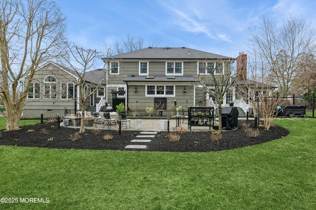 rear view of property featuring fence, a yard, a chimney, a shingled roof, and a patio area