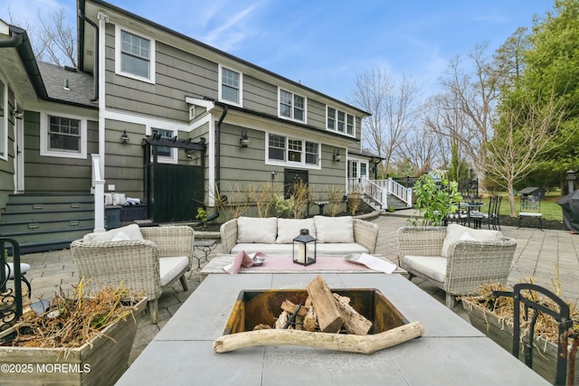 rear view of property featuring an outdoor living space with a fire pit and a patio