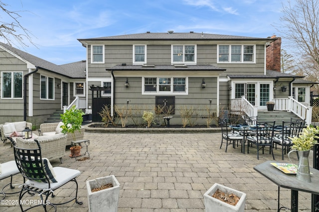 back of property featuring an outdoor living space, a chimney, and a patio area