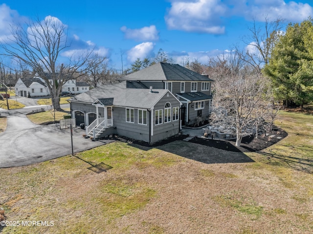 back of property with crawl space, a yard, driveway, and a shingled roof