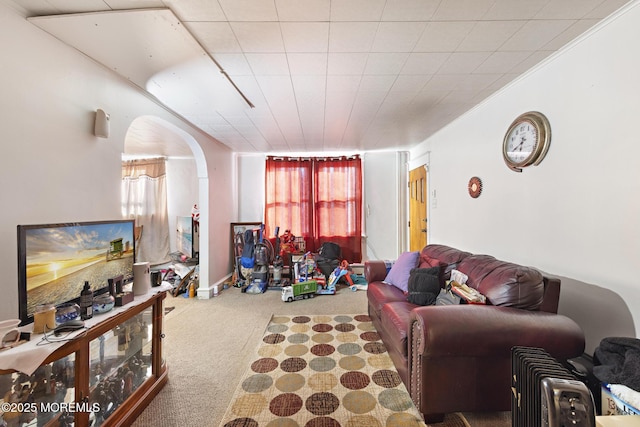 living area with arched walkways, carpet floors, and crown molding