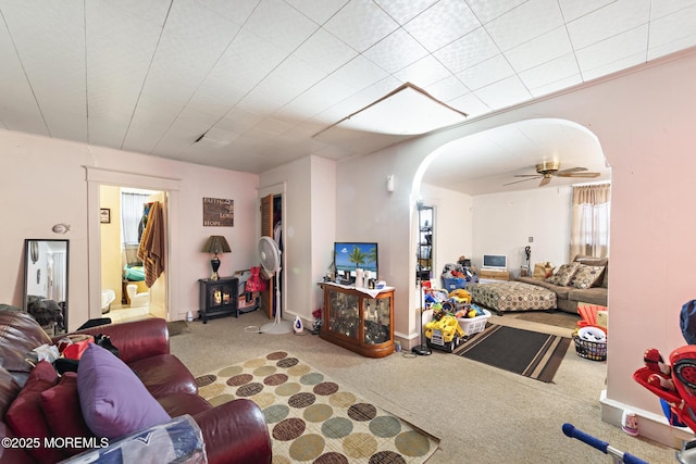 living area with ceiling fan, arched walkways, and carpet flooring