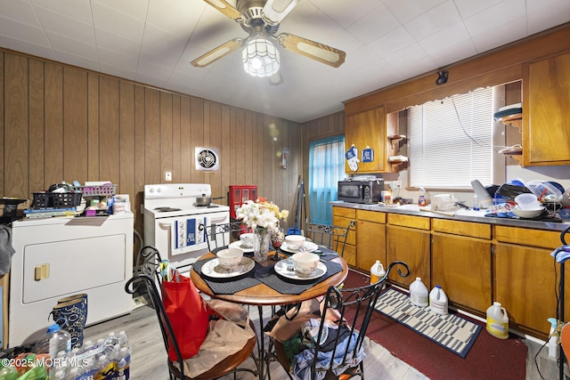 kitchen with visible vents, white range with electric stovetop, light wood finished floors, brown cabinetry, and washer / dryer