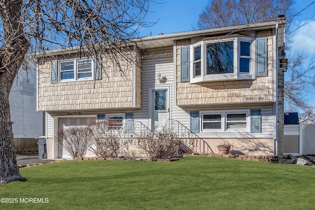 raised ranch featuring an attached garage and a front yard