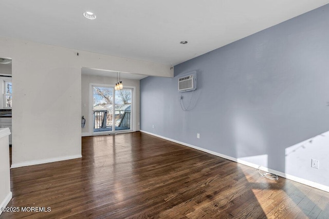 unfurnished dining area featuring a wall unit AC, baseboards, and wood finished floors