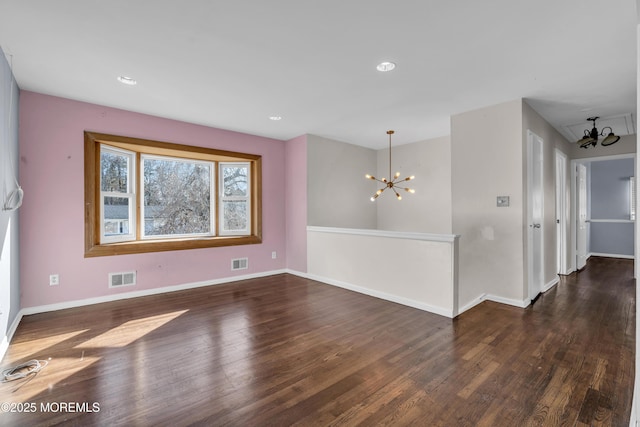 spare room with wood finished floors, visible vents, and an inviting chandelier