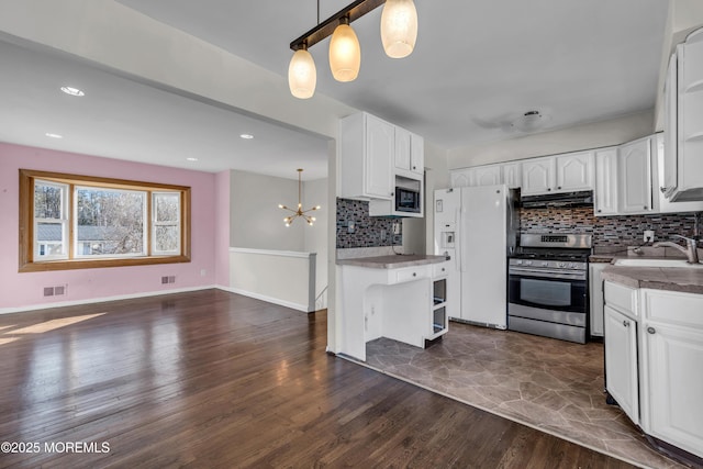 kitchen featuring white refrigerator with ice dispenser, dark wood-style flooring, stainless steel range with gas cooktop, open shelves, and a sink