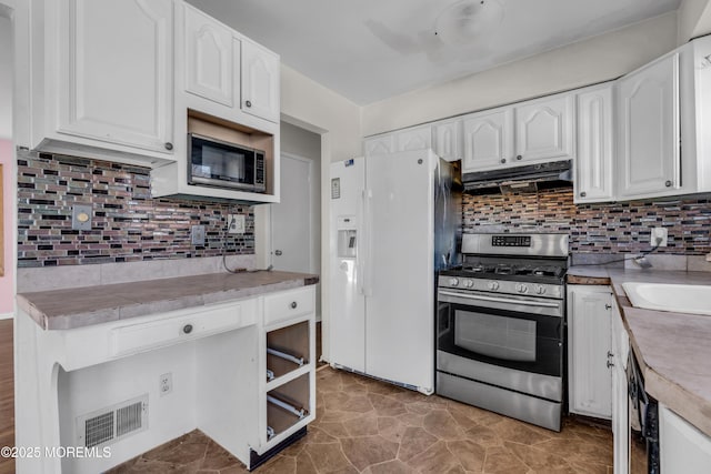 kitchen with white refrigerator with ice dispenser, white cabinets, under cabinet range hood, backsplash, and gas stove